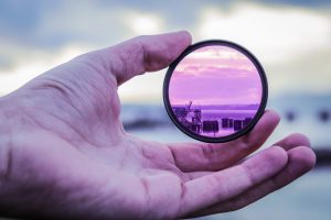 purple hued picture of a hand holding a lens